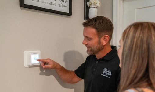 Patrick Chafin (GM) showing homeowner a thermostat